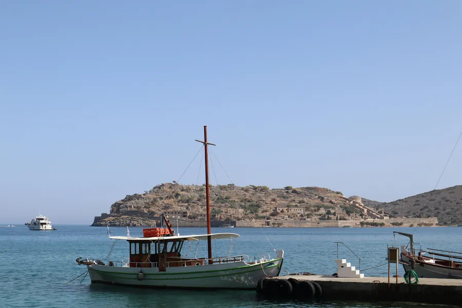 Fishing boat on the shore with Spinalonga island visible in the background at Plaka village