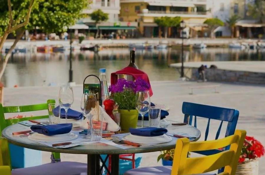 Set dining table with plates and glasses overlooking Lake Voulismeni at Karnagio restaurant