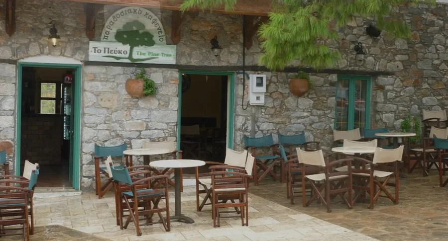 Outdoor seating area and stone decorated facade at Pine Tree restaurant in Plaka